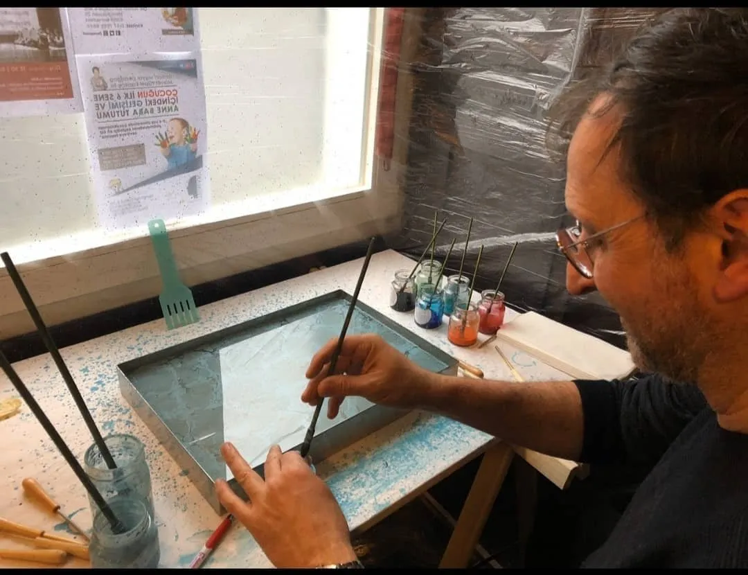 Beim Ebru-Workshop im Vereinshaus (2020) zieht ein Teilnehmer Farbe auf dem Wasser im Becken