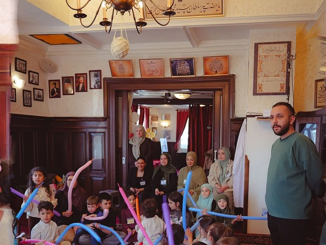 Kinder mit langen Luftballons im Saal des Vereinshauses, Betreuerinnen schauen zu