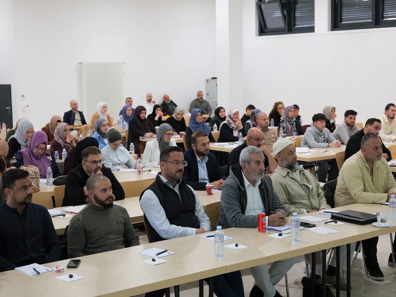 Teilnehmende an langen Tischen beim Seminar im Juni 2026